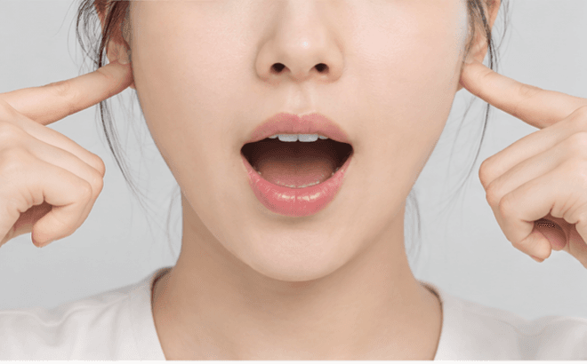 자가진단 1 - 귀 앞 턱관절 부위를 손가락으로 눌러 원을 그리며 마사지하는 모습